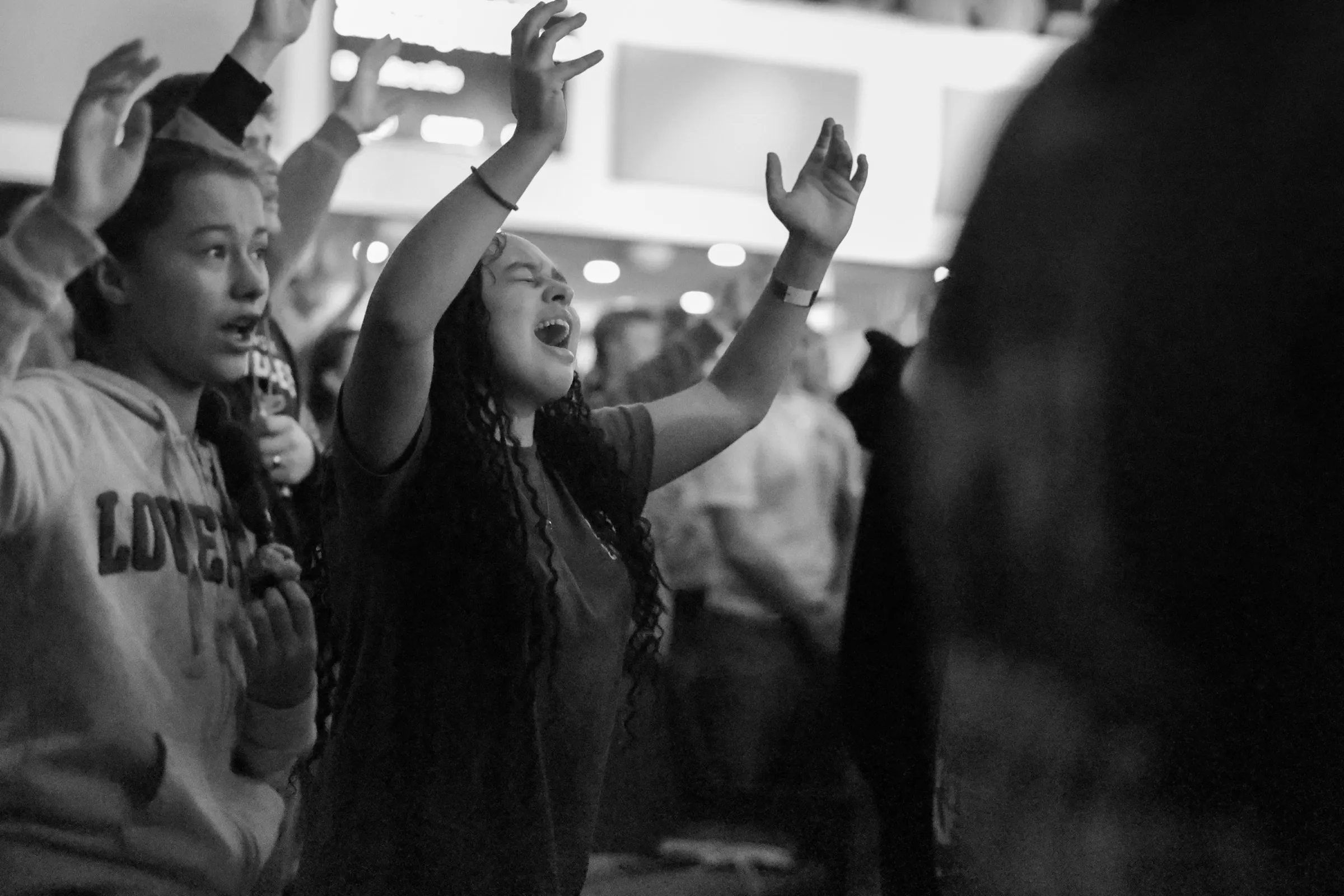 A worshiper with hands raised, photographed in black and white